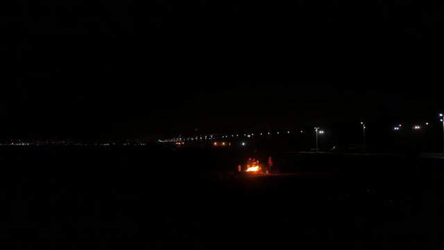 Fire pit at night at the beach with highway in the backround.