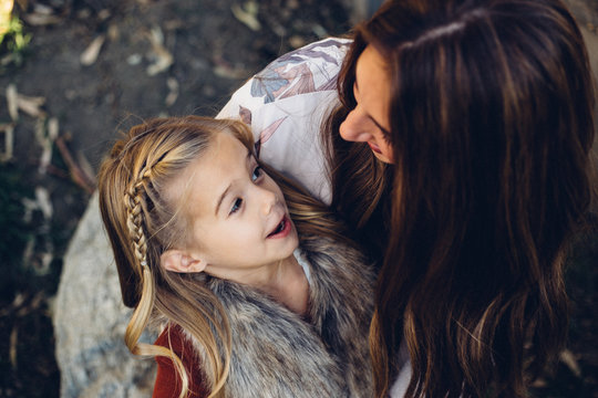 Little Girl Looking Up And Talking To Her Mom Outside While Making A Silly Face