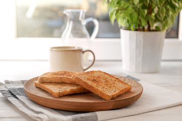 Wooden plate with tasty toasted bread on table