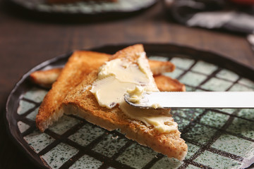 Tasty toasted bread and butter on plate