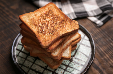 Plate with tasty toasted bread on table