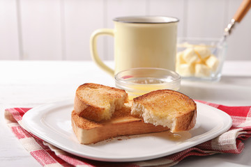 Plate with tasty toasted bread and melted butter on table