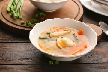 Tasty broth with dumplings on wooden table