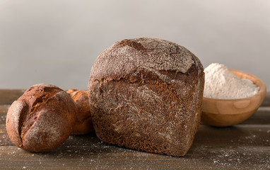 Fresh tasty bread on wooden table against light background