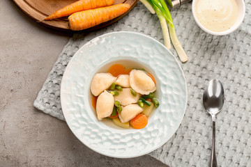 Tasty broth with dumplings on table