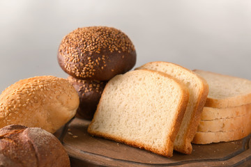 Variety of fresh tasty bread on table against light background