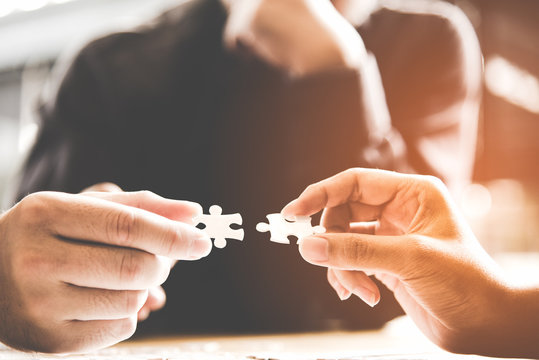 .Businessman team work holding two jigsaw connecting couple puzzle piece for matching to goals target, success and start up new project in office.  Business Concept.