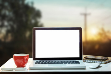 Fototapeta premium Front view of cup and laptop on table in office and background at the sky mountain river and trees front view background. in morning light 