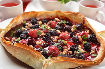 Freshly baked hot strawberry pie served on a white plate with tea    