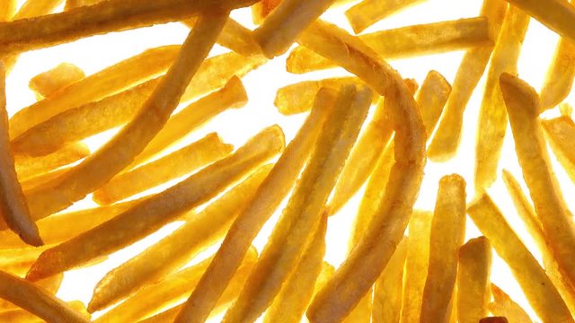Top view of fried potato chips rotating on white background in 4K. Closeup view. Yummy french fries. Popular fast food. 
