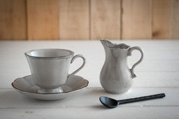 Tea set is Gray on a wooden background. Teapot, creamer, Cup and saucer on the table. Ceramic kitchenware