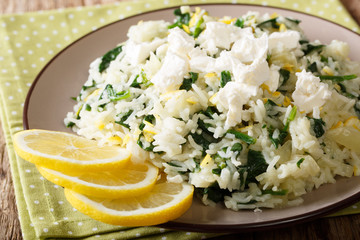 Greek rice with spinach, lemon zest, onion and feta cheese close-up on a plate on a table. horizontal, rustic style