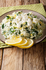 Rice with spinach, lemon zest, onion and feta cheese close-up on a plate on a table. vertical