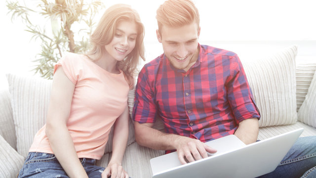 Happy modern couple surfing the net and working on laptop at hom