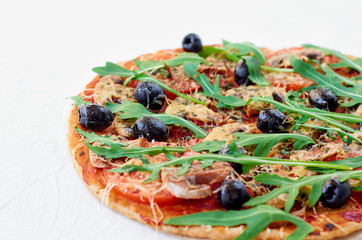 Just baked hot pizza on the white background isolated with free copy space on the left side. Vegetarian pizza with vegetables, black olives and fresh rucola. Side view