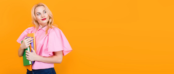Blonde woman in pink blouse with pile of books