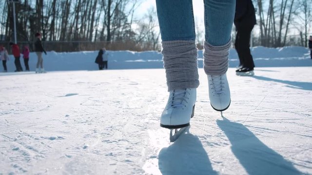 Young woman skating on ice with figure skates outdoors in the snow. Close-up