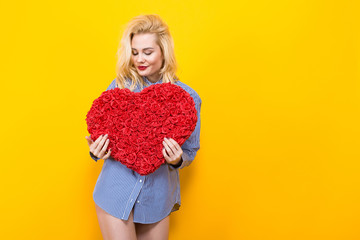 Blonde woman holding big red flower heart