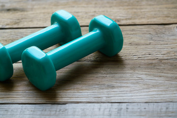 two green dumbbell on wooden table background, sport and healthy concept