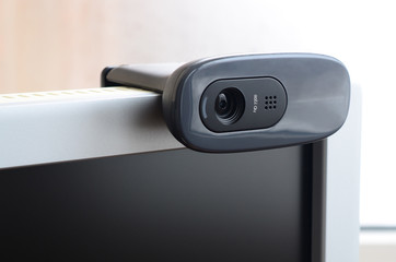 A modern web camera is installed on the body of a flat screen monitor. Device for video...