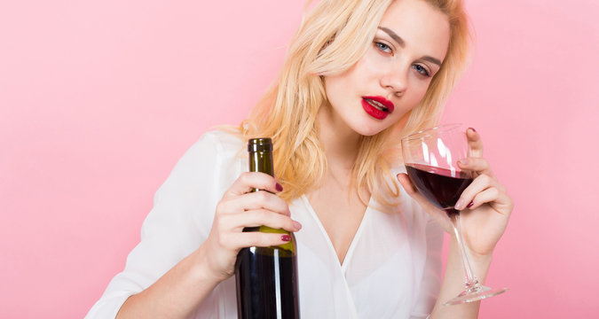 Blonde woman holding wine bottle and glass