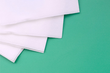 Several white paper napkins lie on a plastic green background