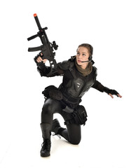 Fototapeta premium full length portrait of female wearing black tactical armour, crouching pose holding a weapon, isolated on white studio background.