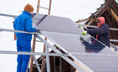 Process of installation of the solar battery by two workers in winter. Outdoors