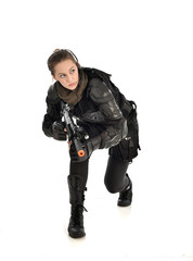 Fototapeta premium full length portrait of female wearing black tactical armour, crouching pose holding a weapon, isolated on white studio background.