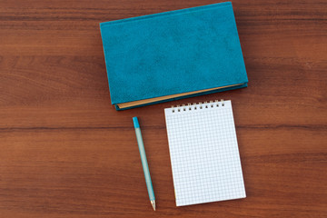 Closed book, notepad and pen on wooden background