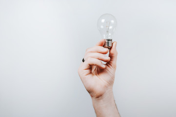 Man's hand holding a light bulb over white background
