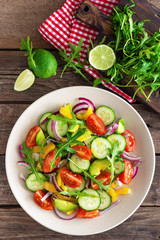 Healthy vegetarian dish, vegetable salad with fresh tomato, cucumber, bell pepper, red onion, avocado and arugula