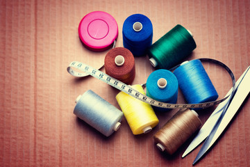 Pile of colorful spools of thread, scissors and measuring meter 