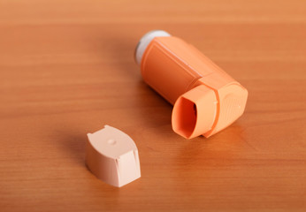 Portable inhaler for asthma sufferers, on background of wooden surface