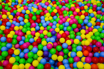 Fototapeta na wymiar Ball pit with colorful plastic balls in children entertainment center. Pool with bright balls background. Fun, game, play.