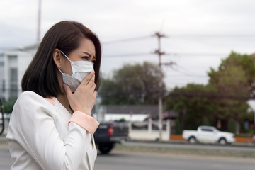 Woman suffer from sick and wearing face mask., asian woman in protective mask feeling bad on the street in the city with air pollution.
