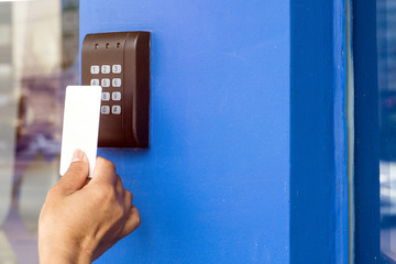 Door access control - young woman holding a key card to lock and unlock door., Keycard touch the security system to access the door
