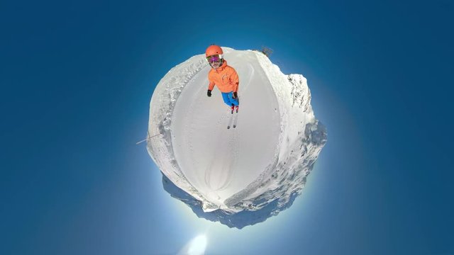 360VR man skiing on ski slope on sunny winter day with clear blue sky on little planet earth
