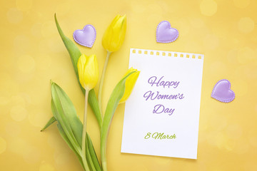 Women's Day greeting message with yellow tulips on ayellow background. Top view.