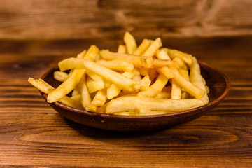Ceramic plate with french fries on wooden table