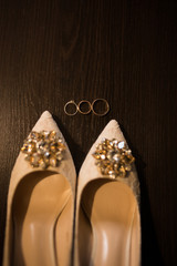 Golden wedding ring near the beige shoes with shiny stones on them. Wedding details