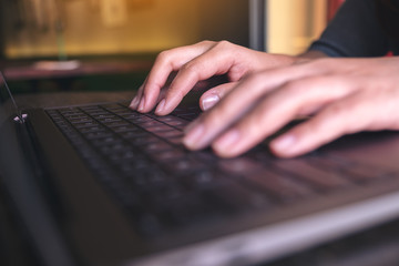 Closeup image of hands working and typing on laptop keyboard on the table