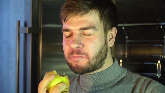 a man with a beard eats a yellow apple