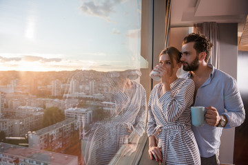 young couple enjoying evening coffee by the window