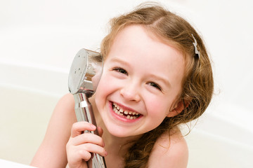 Laughing girl playing with shower in the bathroom