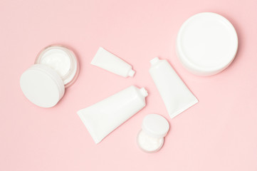 White cosmetic tubes and cream containers top view on pink background - 193248322