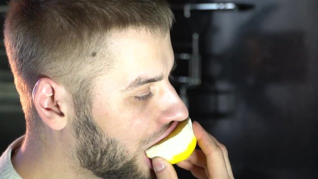 a man eats a juicy lemon wrinkling his face, sour