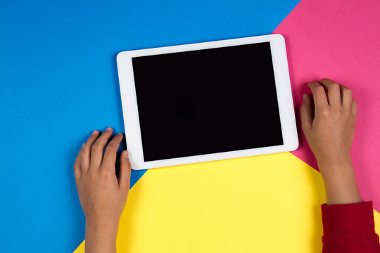 Kid hands with tablet computer on colorful background