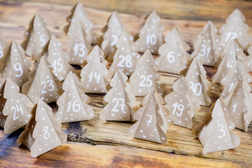 Handmade Christmas advent calendar Christmas trees Kraft paper with numbers in wood background.