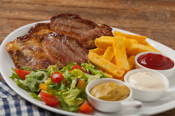 Grilled pork neck served with French fries and salad.